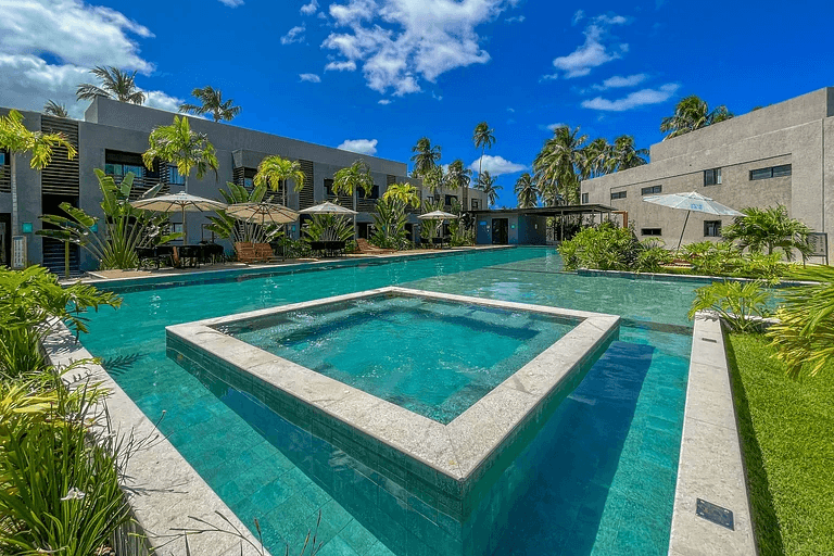 Piscina do condomínio resort cercada por jardins e coqueiros
